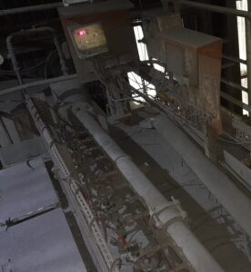 Industrial dust collection system showing a compressed-air manifold, pulse valves and control equipment inside a processing plant.