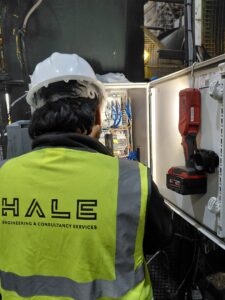 Hale Engineering engineer beside an open bin pre-tipper control panel during the PLC upgrade.